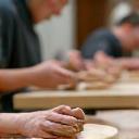 People participating in a pottery workshop, hands on clay