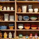 Display of various handcrafted items including ceramics, textiles, and wood carvings in a store setting